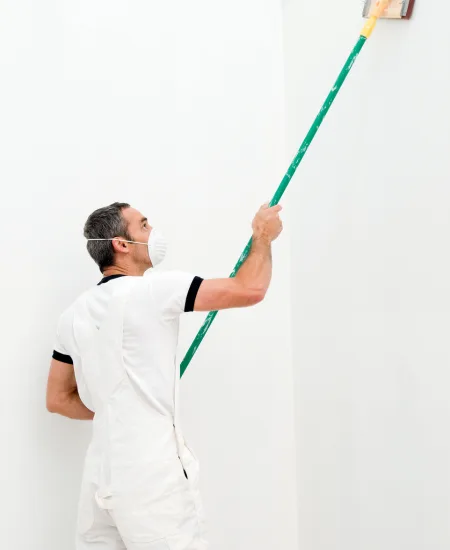 A cleaner rolling paint along a freshly finished wall