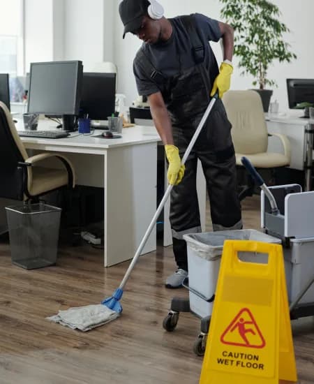 A cleaner mopping the floor of an office space